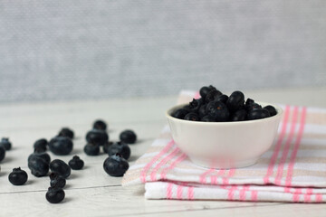 a bowl of blueberry and berries on a napkin on wooden background