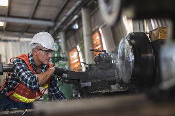 worker is working on a lathe machine in a factory. Turner worker manages the metalworking process of mechanical cutting on a lathe