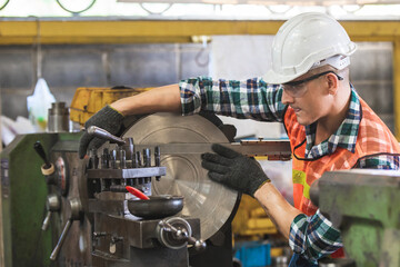 worker is working on a lathe machine in a factory. Turner worker manages the metalworking process...