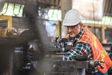 worker is working on a lathe machine in a factory. Turner worker manages the metalworking process of mechanical cutting on a lathe