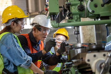 Asian Group industrial manager man demonstration and training mechanic worker woman  operating industrial lathe machine. Industry and engineering people technology concept .