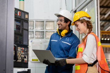 portrait of an industrial man and woman engineer with tablet in a factory. Factory worker is programming a CNC milling machine with a tablet computer