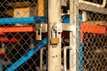 A heavy duty used steel padlock is locking on sliding metal gate of the warehouse storage,...