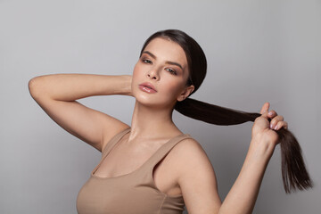 Beautiful young woman touching her ponytail hairstyle with smooth straight hair - obrazy, fototapety, plakaty