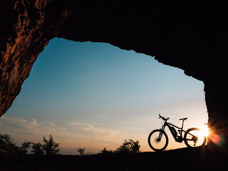 silhouette of a e-bike or bike at sunset in a cave - 437340360