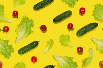 Food colorful seamless pattern - bright cherry tomatoes, green gherkin cucumber, salad leaves in hard light with shadow on yellow background, flat lay.