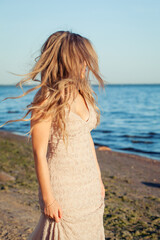 Fototapeta na wymiar Portrait of blonde woman with blowing hair in front of the sea, woman fashion sea pictures