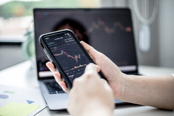 Stock investors hold a phone, open a stock chart viewer to read stock price charts, analyze purchases. Cryptocurrency stocks are popular with both new and old investors. investing in stocks.