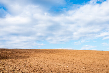 Fototapeta na wymiar Plowed brown field and white clouds on blue sky.cloudy sky over brown field.Spring summer day.