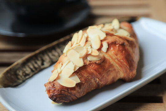 Selective focus on almond crossiant with hot coffee on background in home morning eating