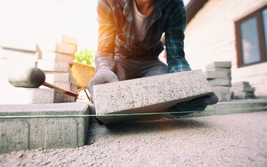 Worker lining paving slabs path