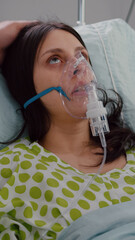 Close up of medical doctor putting oxigen mask to sick woman while resting in bed having...