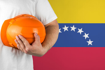 Worker with Venezuela flag on background for working on labor day. Construction concept.