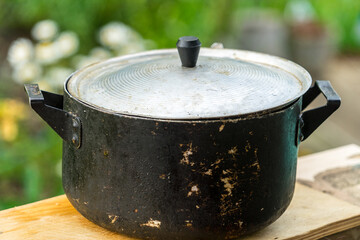 A dirty old metal pot. Close-up photo.