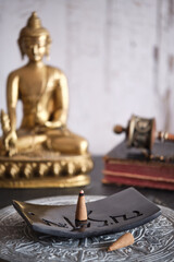 Tibetische R&auml;ucherkegel auf schwarzem Specksteinhalter mit goldenem Buddha und Gebetsm&uuml;hle
