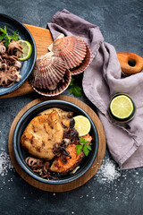 Grilled seafood variety with vegetables on dark background.
