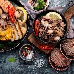 Grilled seafood variety with vegetables on dark background.