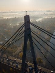 Obraz premium Aerial view of Pivnichnyi Bridge at sunrise with Ukraine flag on top. Kyiv city in a morning fog.
