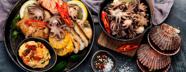 Grilled seafood variety with vegetables on dark background.