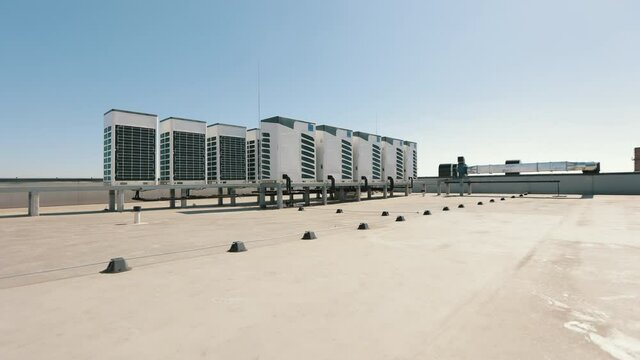 An air conditioning system of two rows of air conditioners is located on the roof of the business center. The camera is moving closer to the subject. Nice sunny day. 4K