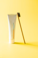 Wooden toothbrush with  tube of  toothpaste  on yellow background. Eco dental care for oral health...