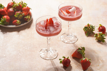 Two glasses with red strawberry dessert with ice cubes and crashed ice and strawberry slices