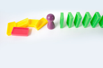 close-up shot of a collapsing business being rescued by a special employee-manager. Line of colored domino cubes falling, one chip stops falling with copy space, domino effect concept in business