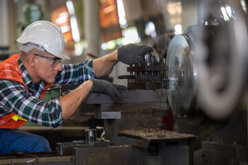 worker is working on a lathe machine in a factory.