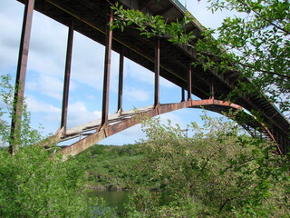 Bottom view of the power and grandeur of the arch bridge against the background of heavy gray clouds.