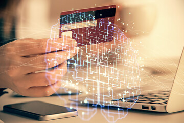 Double exposure of woman on-line shopping holding a credit card and brain hologram drawing. Data...