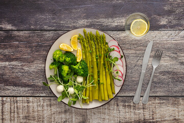 Delicious healthy breakfast, broccoli with asparagus, microgreens with mozzarella and radishes and lemon slices