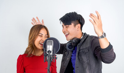 Young asian couples with headphone sing in chorus with microphone and pop filter on tripod stand.