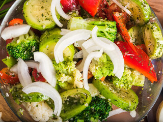 Raw vegetables with spices in a glass bowl, cooked for grilling, top view, close-up - delicious vegetarian dish, healthy food