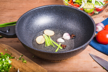 The beginning of the preparation of traditional Chinese and Asian dishes - frying in oil of ginger, garlic, onion and spices. Preparing aromatic oil for cooking in Chinese cuisine. 
