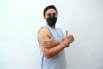 man wearing face mask showing vaccinated arm