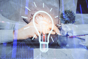 Double exposure of man's hands holding and using a digital device and bulb hologram drawing. Idea concept.