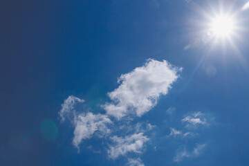 Naklejka na ściany i meble Sunbeams in summer with white clouds on a blue sky background