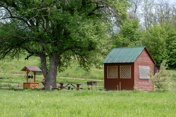 Water well, table and wooden gazebo under the green tree
