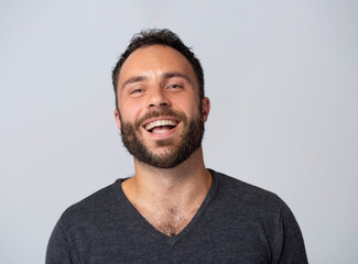 Mature contented man with beard smiling on white background with gray jumper