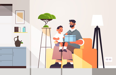 young father holding gift box for son parenting fatherhood concept dad giving holiday present to his kid at home