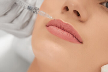Close up of beautician in white rubber gloves doing injection for lip augmentation with professional preparations. Concept of beauty procedures in salon. 