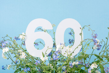 Number sixty among blue forget-me-not flowers. .Birthday, anniversary, jubilee concept.