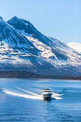 Motorboat in a norwegian fjord with snow capped mountains