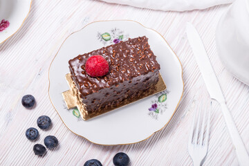 Piece of berry cake decorated with fresh berries on wooden background