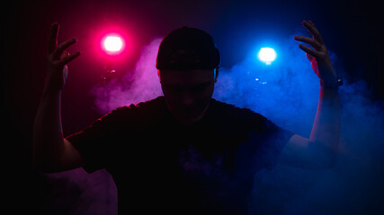 The silhouette of a man against the background of smoke, consecrated by red and blue light