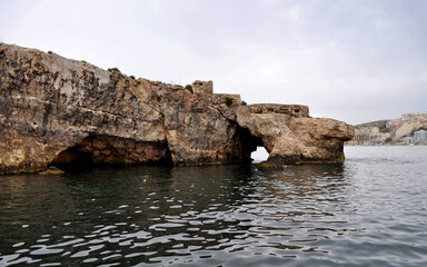 Photo of sea caves and a rock arch made by a boat around the coast of Malta, Europe.