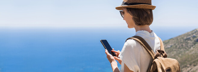 Tourist woman using mobile phone by the sea panoramic banner