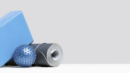 Rolled blue yoga mat and foam block or brick, massage ball. Blue fitness and exercise concept...