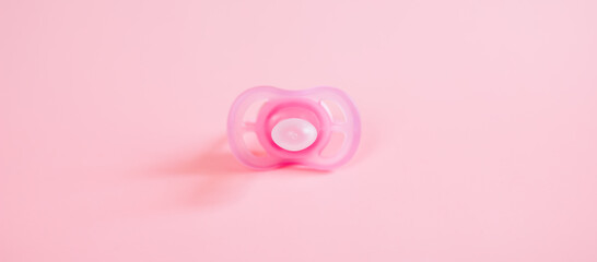 Orthodontic pacifier in pink color, isolated on a pink background. Shows signs of use. Space for text on a dummy background