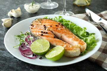 Concept of tasty eating with grilled salmon on black smokey table